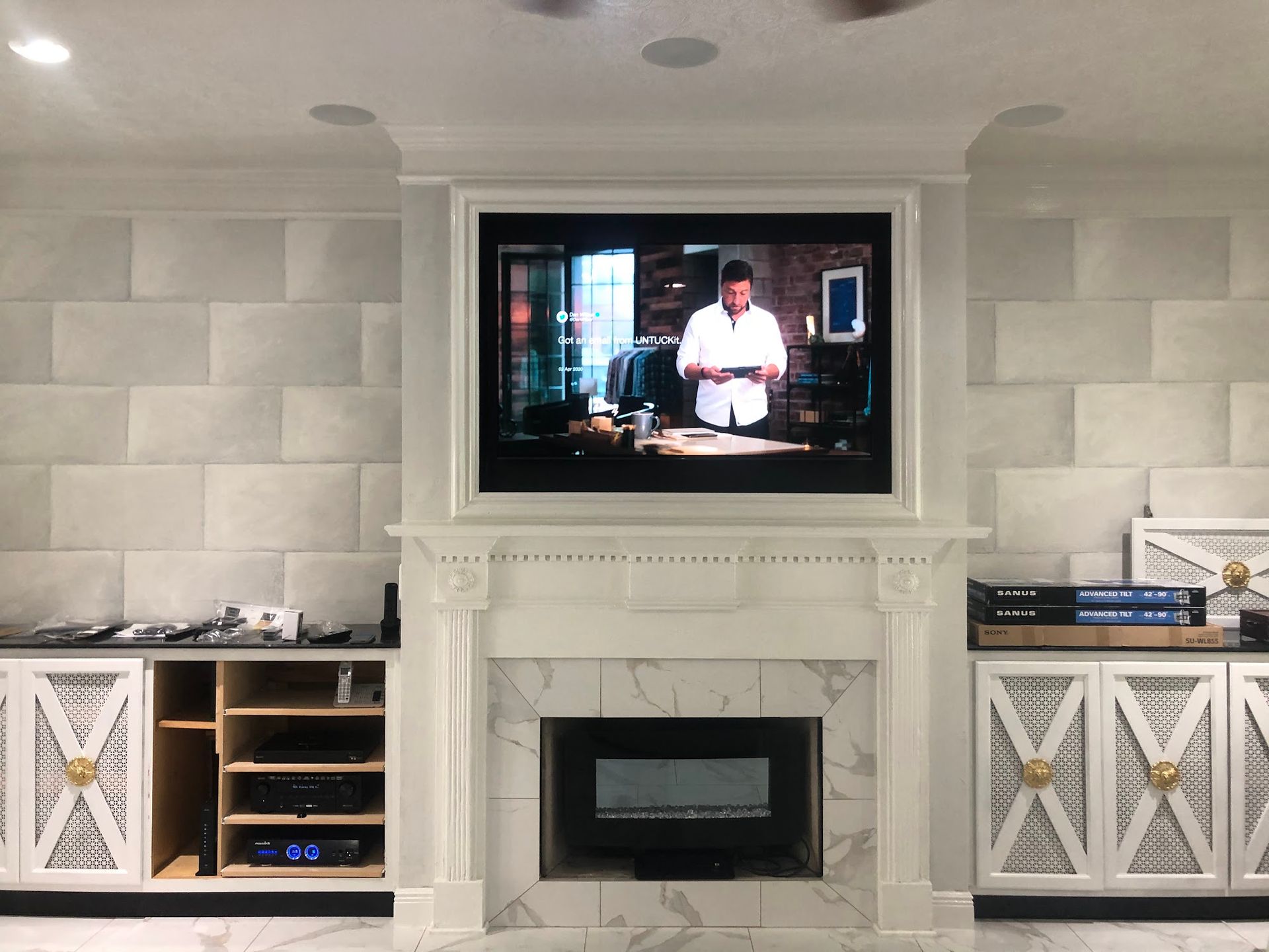 Living room with a TV above a fireplace; white cabinets and textured wall.