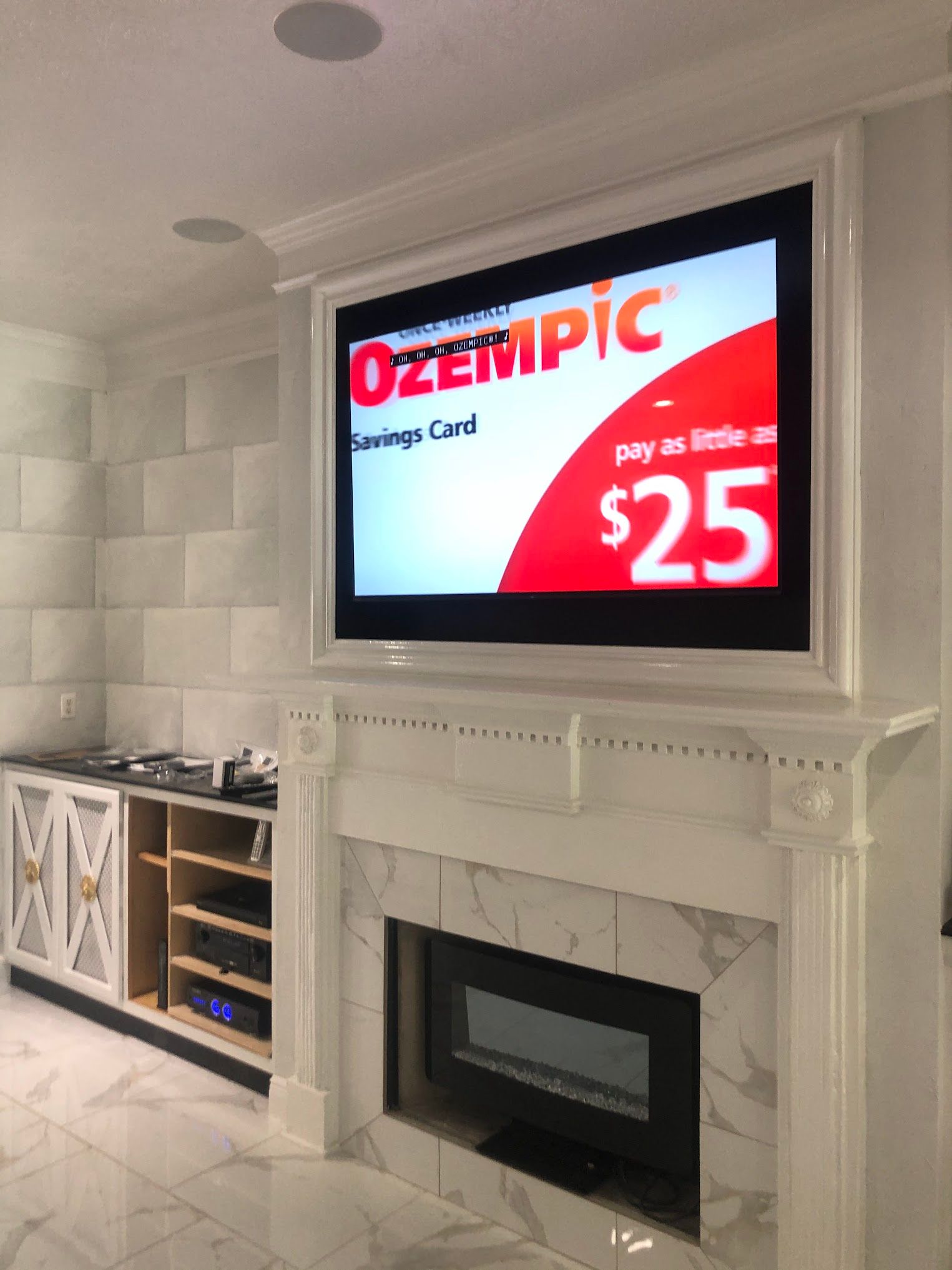 Television above a white fireplace, displaying an Ozempic Savings Card