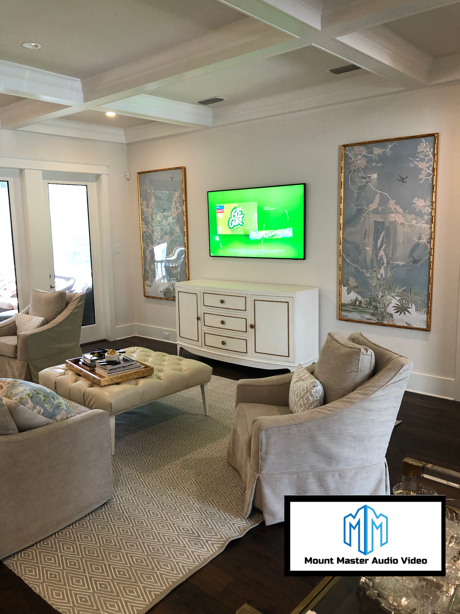 Living room with white walls, furniture, and TV; light gray rug and dark wood floors.