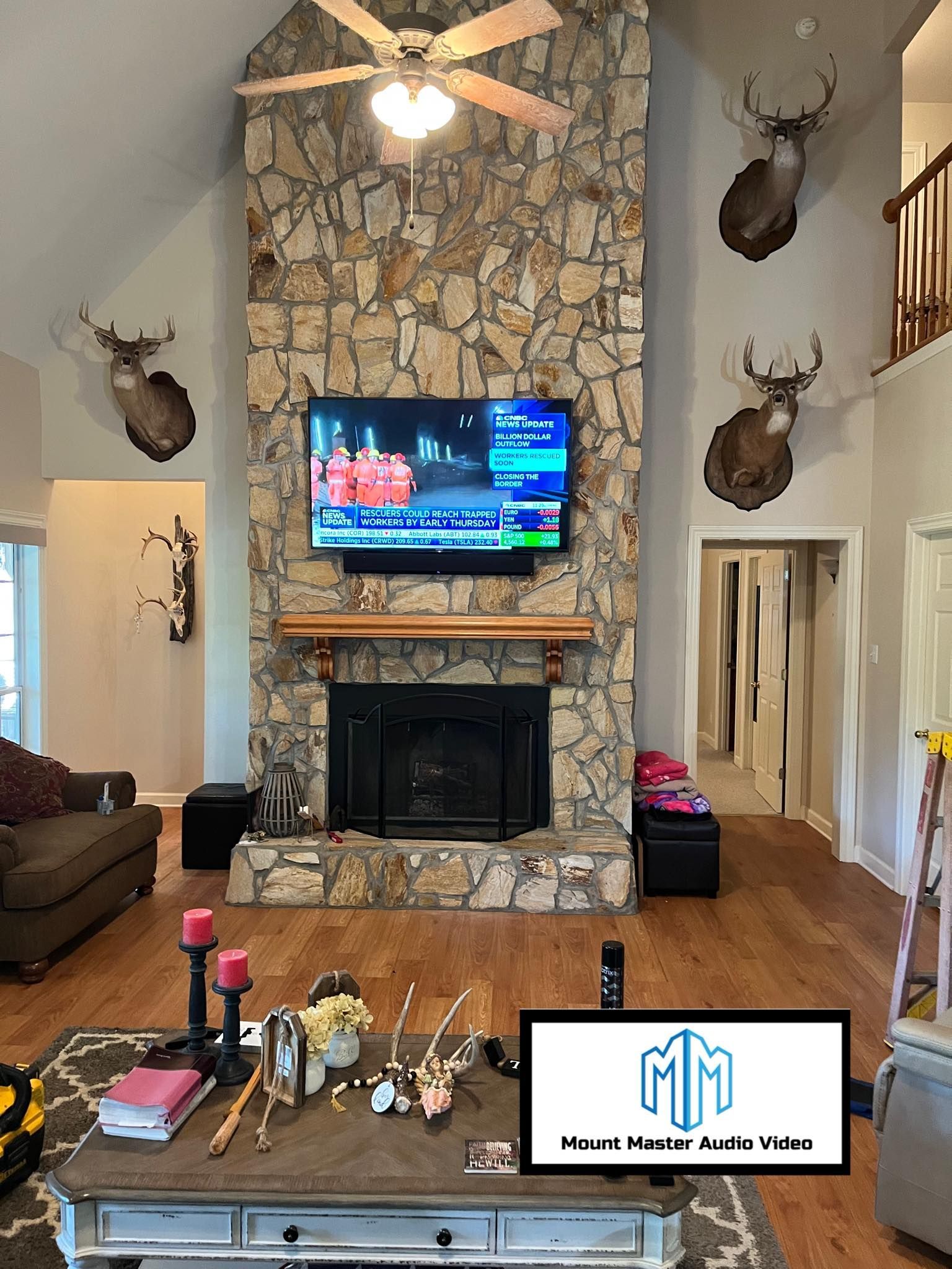 Living room with stone fireplace, TV, deer heads, sofa, and coffee table.