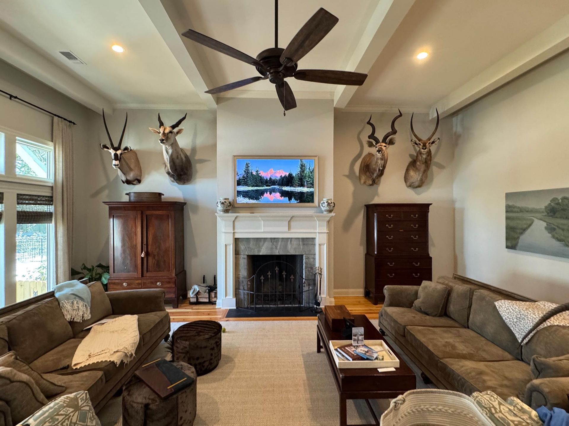 Living room with taxidermy, fireplace, and brown couches.