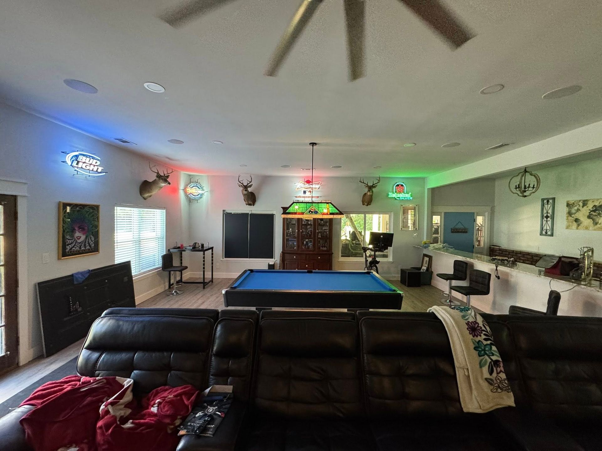 Game room with pool table, leather couch, neon signs, mounted deer heads.