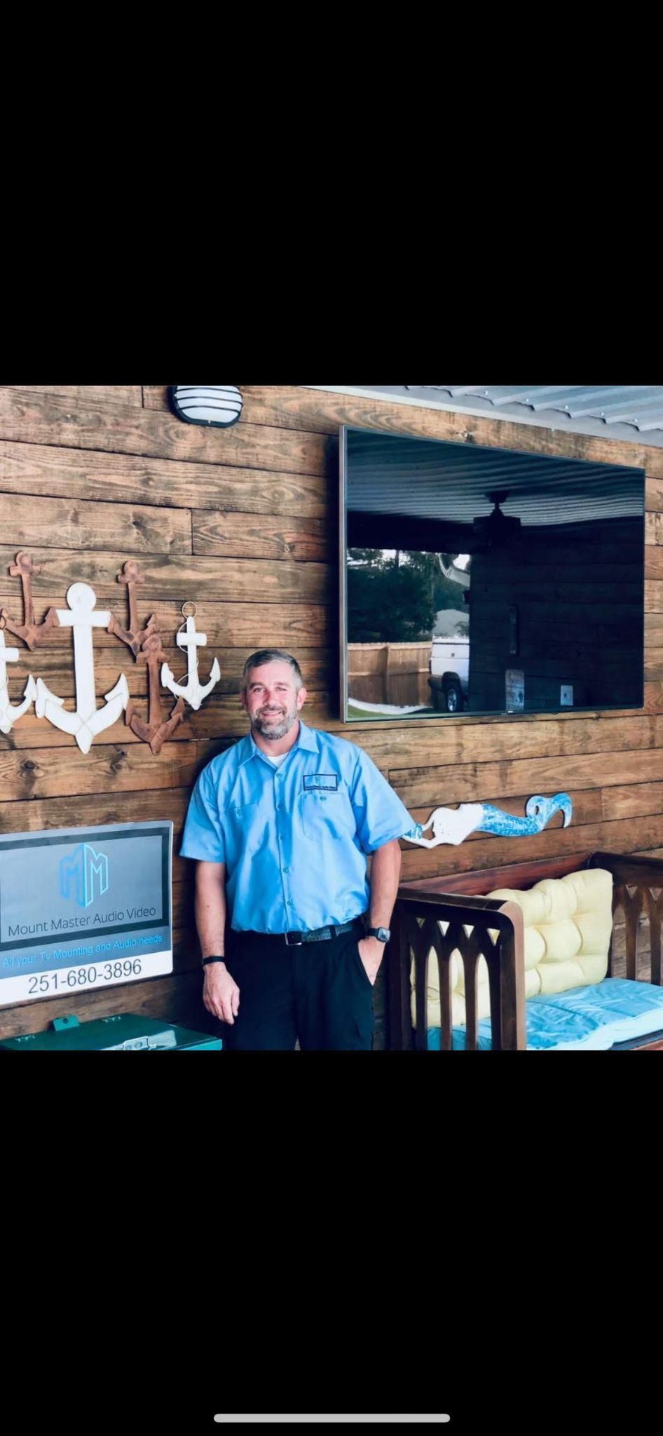 Man in blue shirt stands by wood wall with nautical decor and mirror.