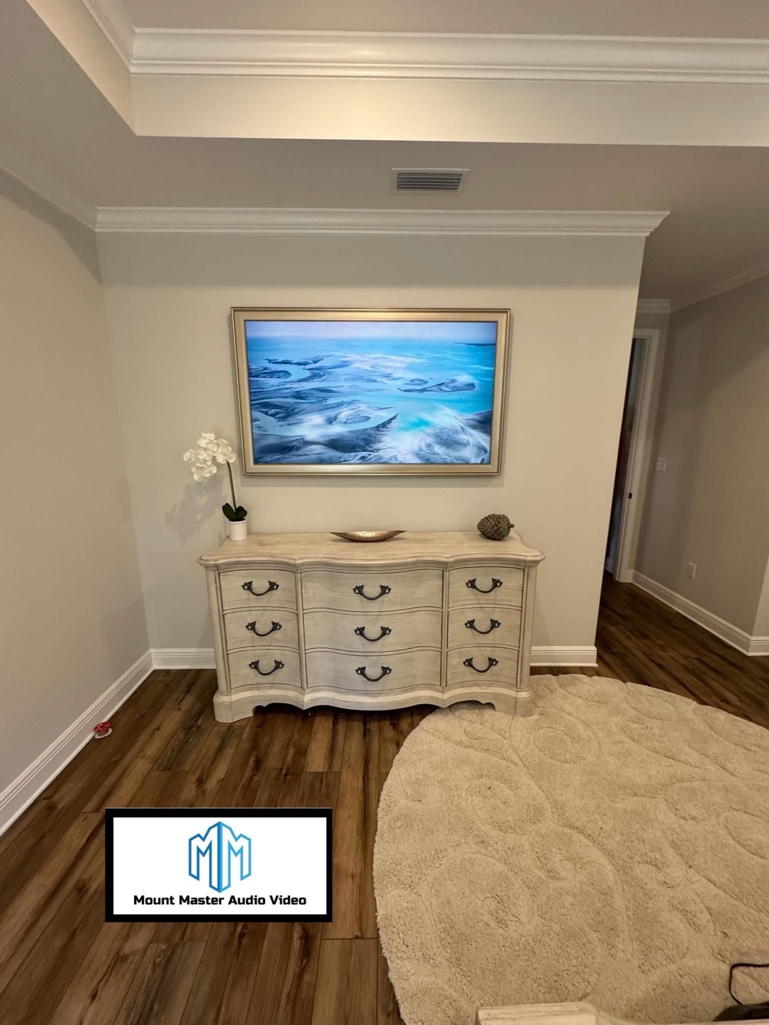 A coastal-themed living room featuring a framed artwork, a distressed white dresser, and a circular rug.