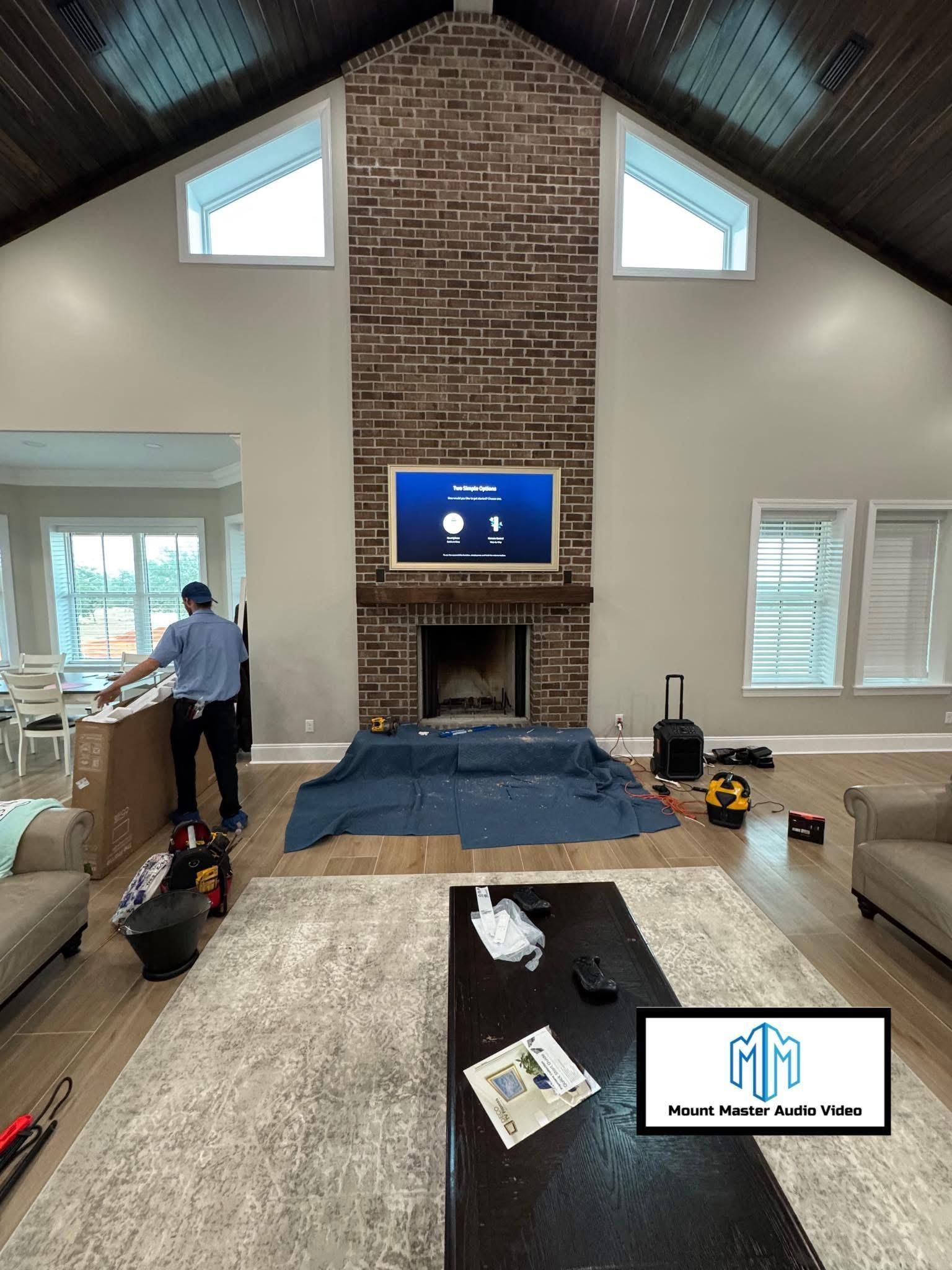 Living room with brick fireplace, TV, and workers setting up.