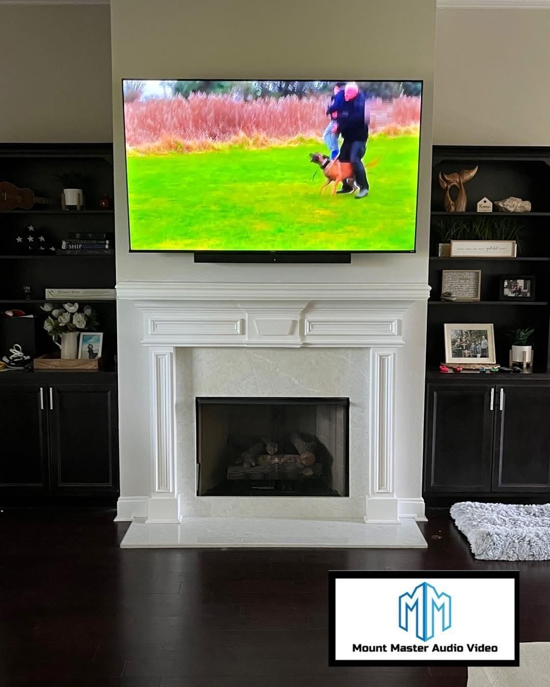 TV mounted above fireplace with bookshelves, showing people on a grassy field.