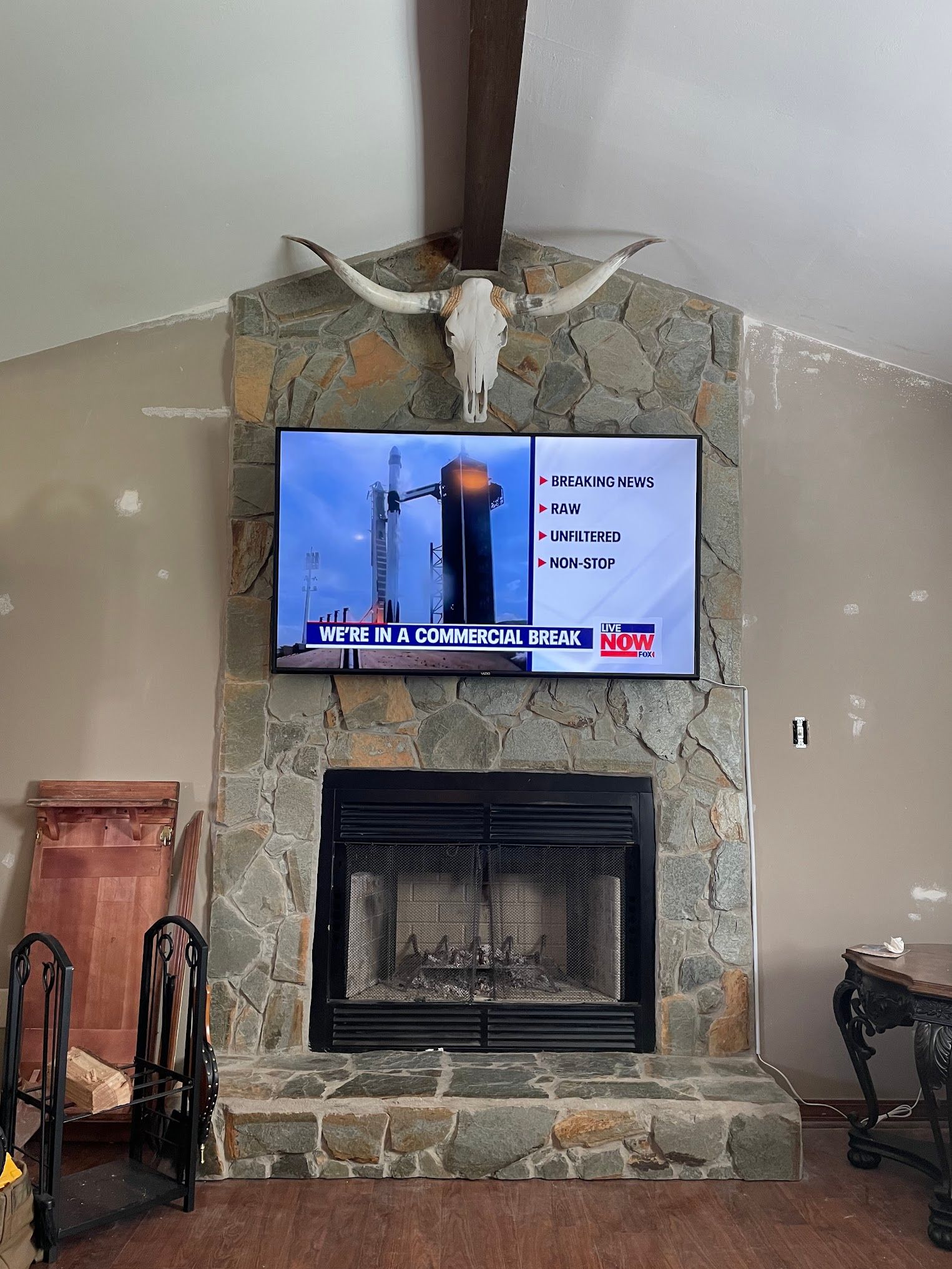 A fireplace with a TV, adorned with a skull. The TV shows a rocket launch.