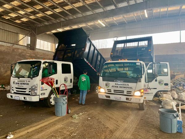 Two dump trucks are parked next to each other in a warehouse.