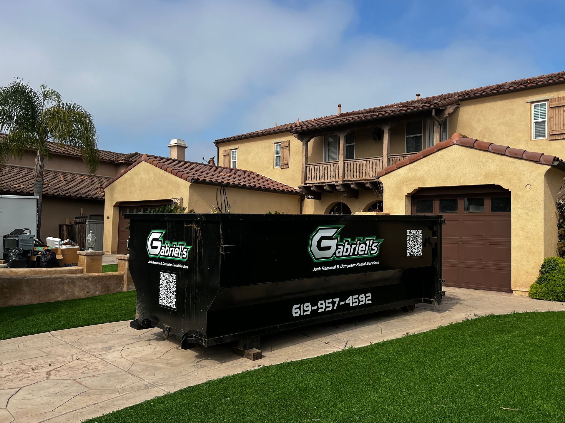 A large dumpster is parked in front of a large house.