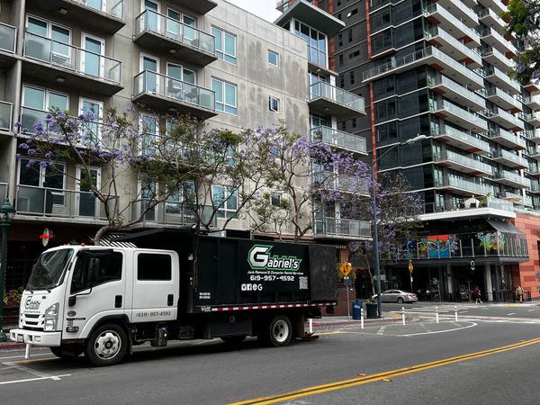 A garbage truck is parked on the side of the road in front of a building.