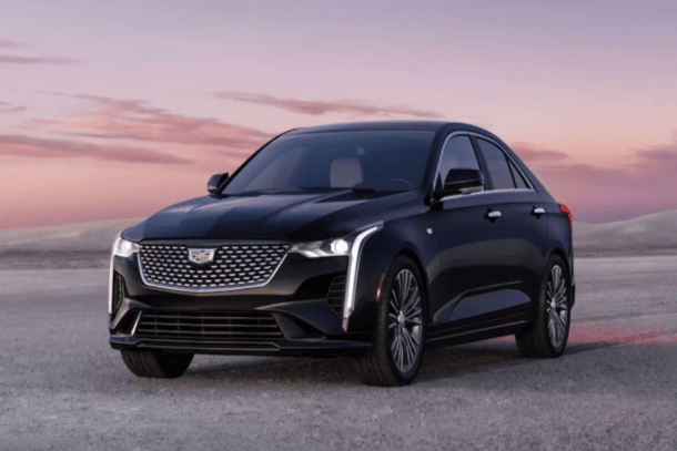 A black cadillac is parked in the middle of a desert.