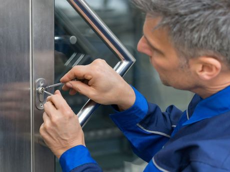 A Man In A Blue Shirt Is Using A Key To Open A Door