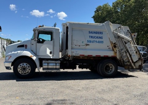 White Saunders Trucking garbage truck parked outdoors on a sunny day.