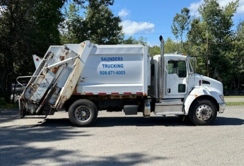 White Saunders Trucking garbage truck parked outdoors. White Saunders Trucking garbage truck parked outdoors.