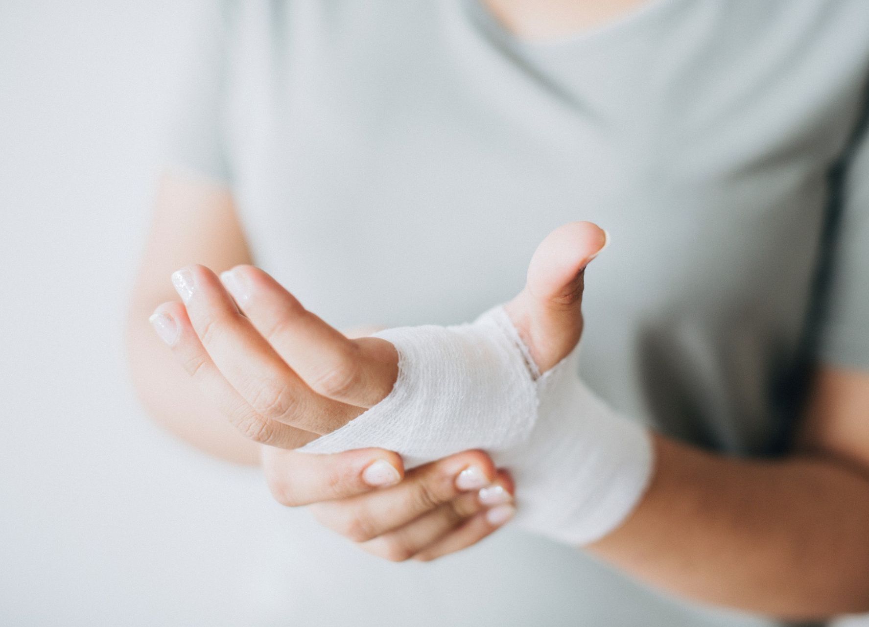 A woman is holding her wrist with a bandage on it.