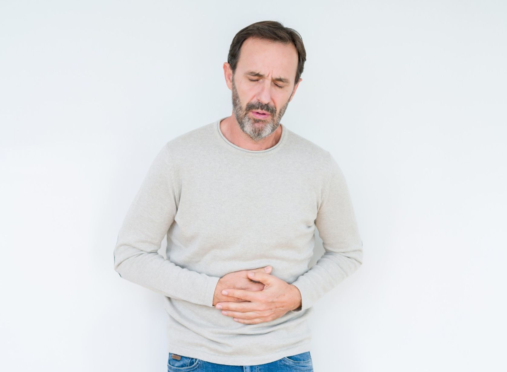 A man with a beard is holding his stomach in pain.