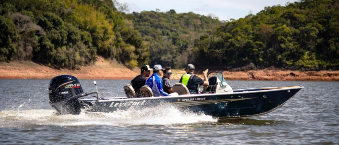 Um jet ski turquesa e branco em águas calmas perto de uma costa verdejante.