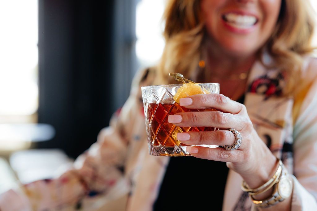 A Woman Holding a Whiskey Cocktail From Six-Mile Ordinary in Columbia, MO.