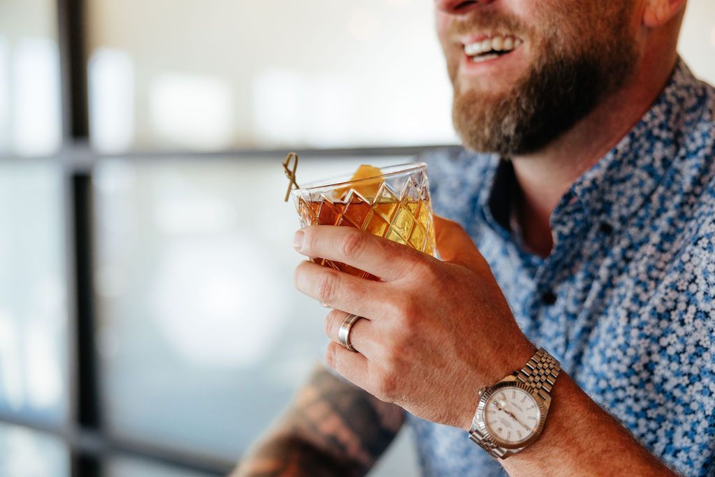 A Man Holding a Whiskey Cocktail From Six-Mile Ordinary in Columbia, MO.