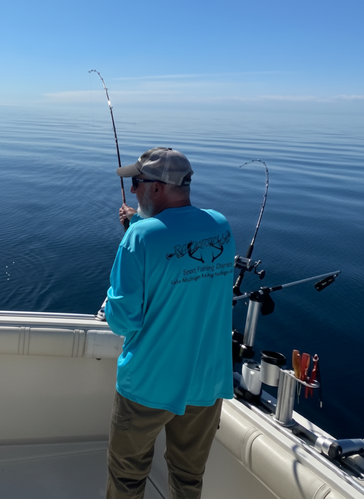 Man fishing from a boat on a calm, blue lake under a sunny sky.