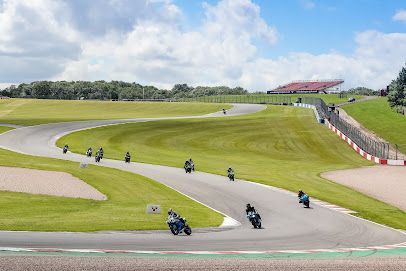 Canal scene: boat, water, path, bridge, and house surrounded by green trees on a sunny day.