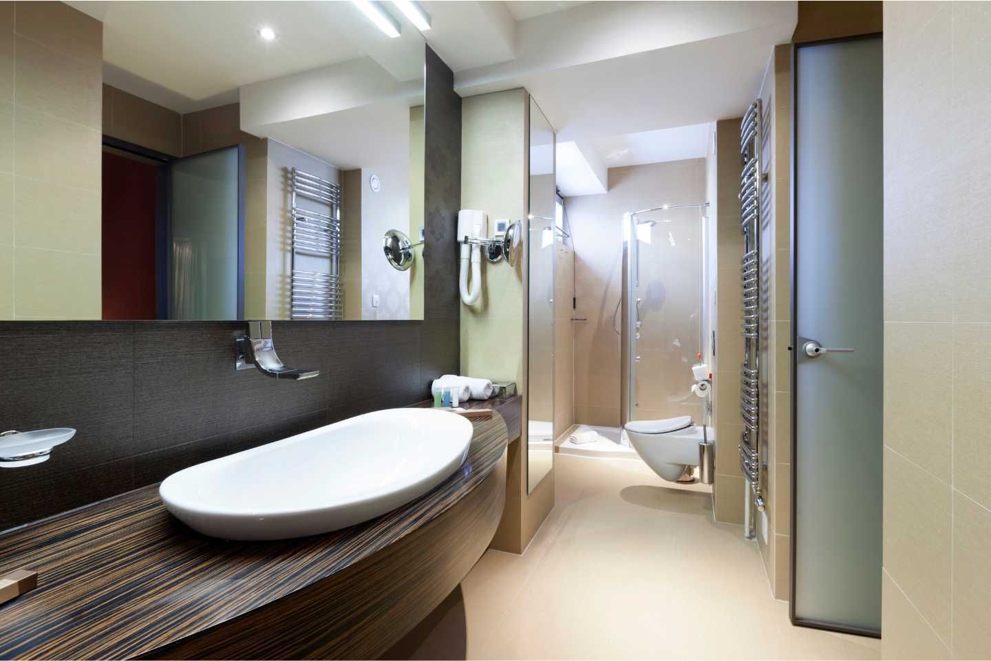 Modern bathroom with white oval sink, large mirror, and glass shower. Neutral tones.