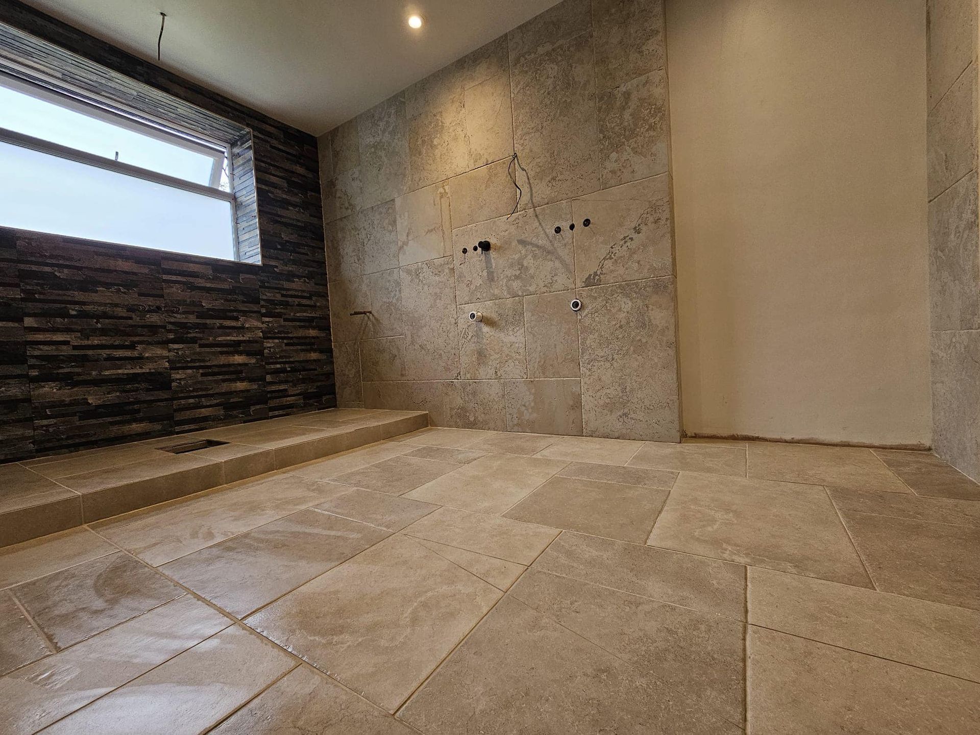 Bathroom with stone tiles, stone accent wall and window with stone surround.