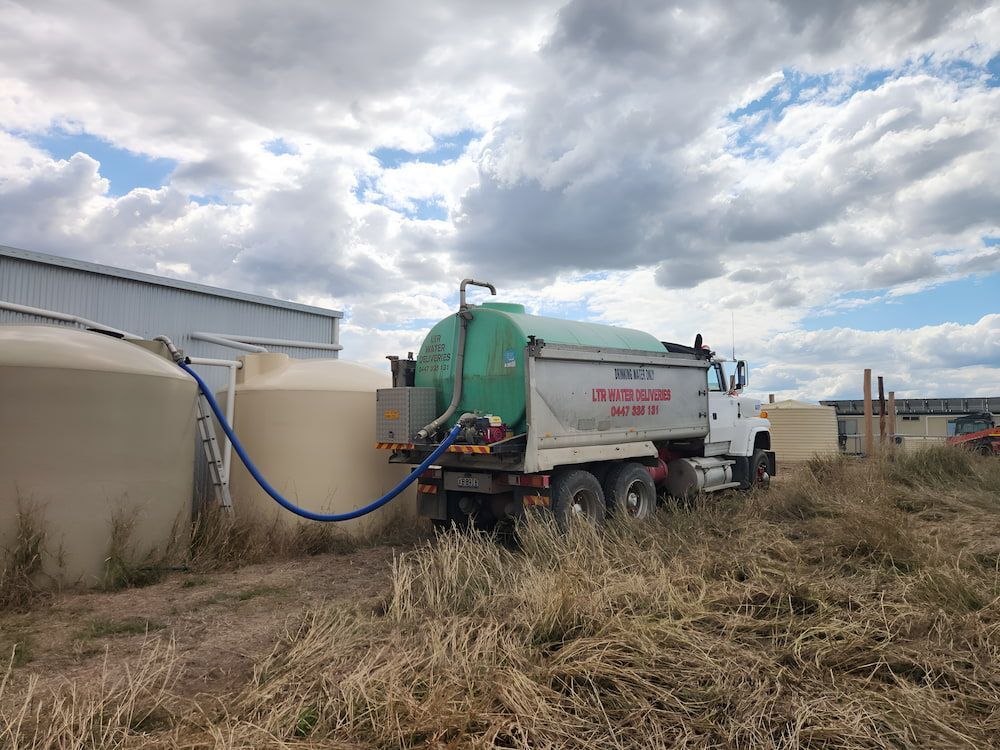 A Water Truck Is Driving Through A Field With A Hose — LTR Water Deliveries In Wamuran, QLD