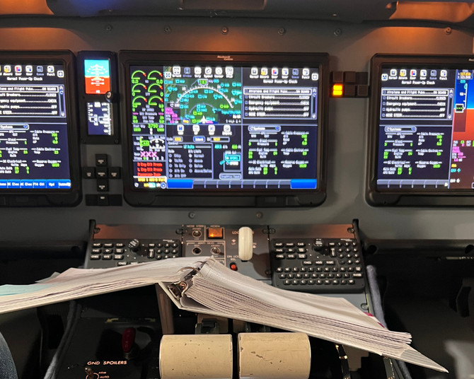 Cockpit instruments in airplane, showing flight data, with papers on console.