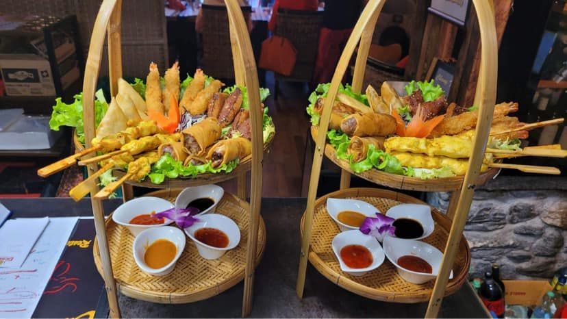 Deux plateaux en bois remplis de nourriture et de sauces sur une table.