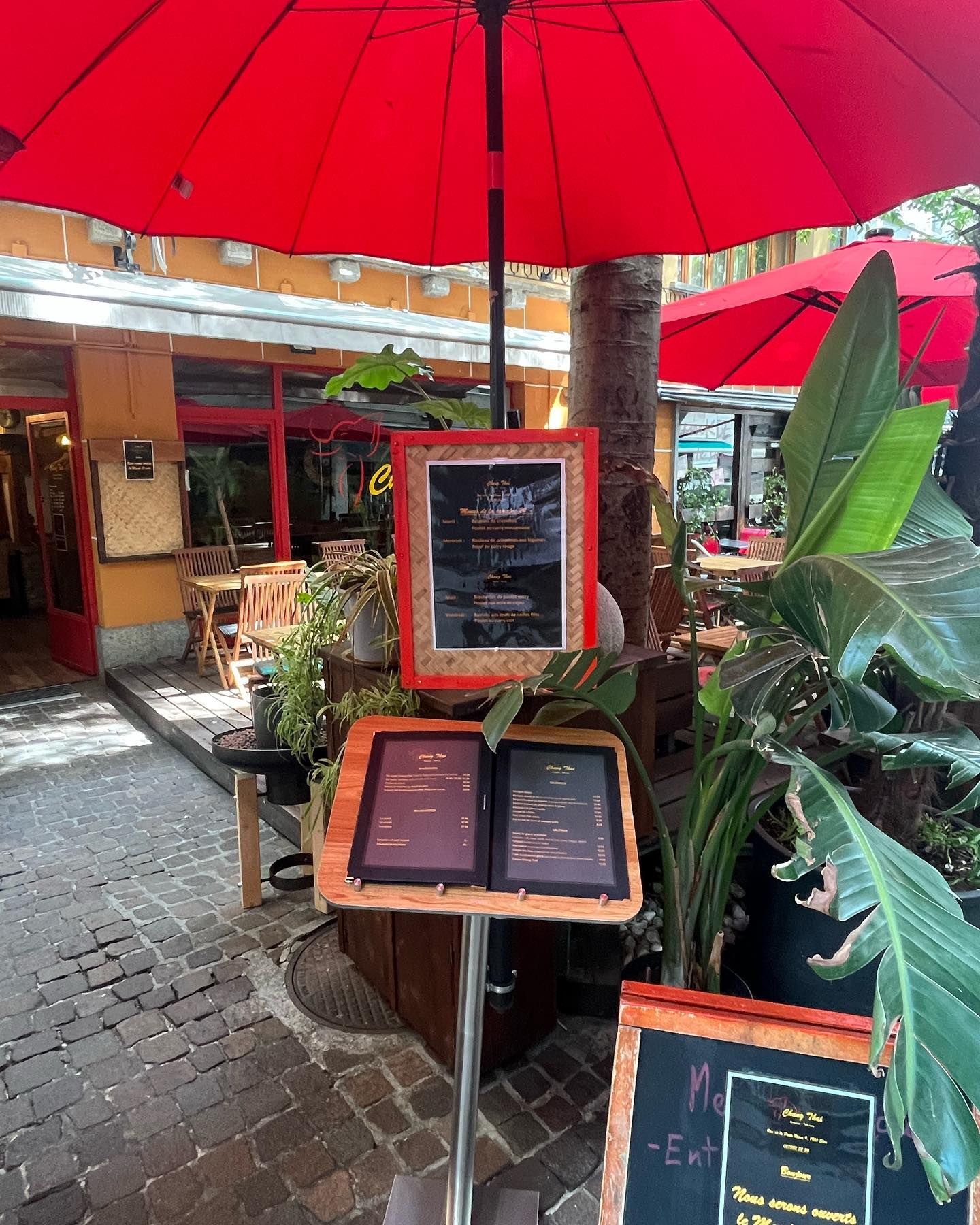 Un parapluie rouge est posé devant un restaurant.