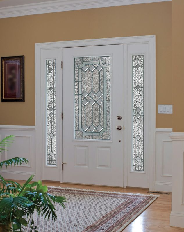 Front entry with white double doors and decorative glass panels in a tan-walled foyer