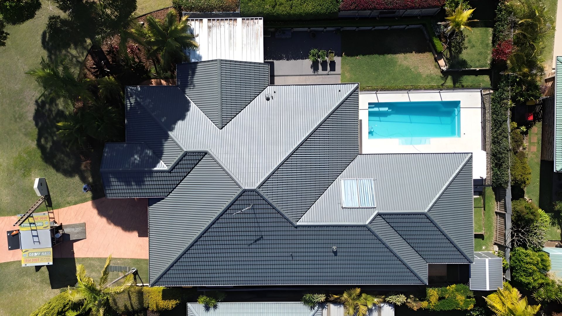 Aerial View of A House with A Pool. Gray Roof, Blue Pool, and Green Yard — Geoff Hall Roofing in Harrington, NSW