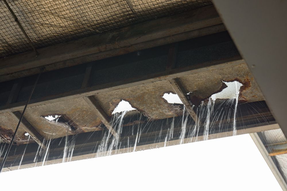 Water Pouring Through Holes in A Deteriorating Concrete Ceiling — Geoff Hall Roofing in Frederickton, NSW