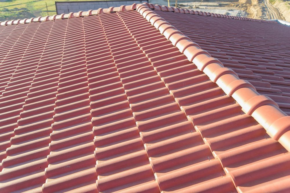 Red tiled roof on a building, angled view. Rows of tiles, sunlight creates shadows — Geoff Hall Roofing in Wauchope, NSW