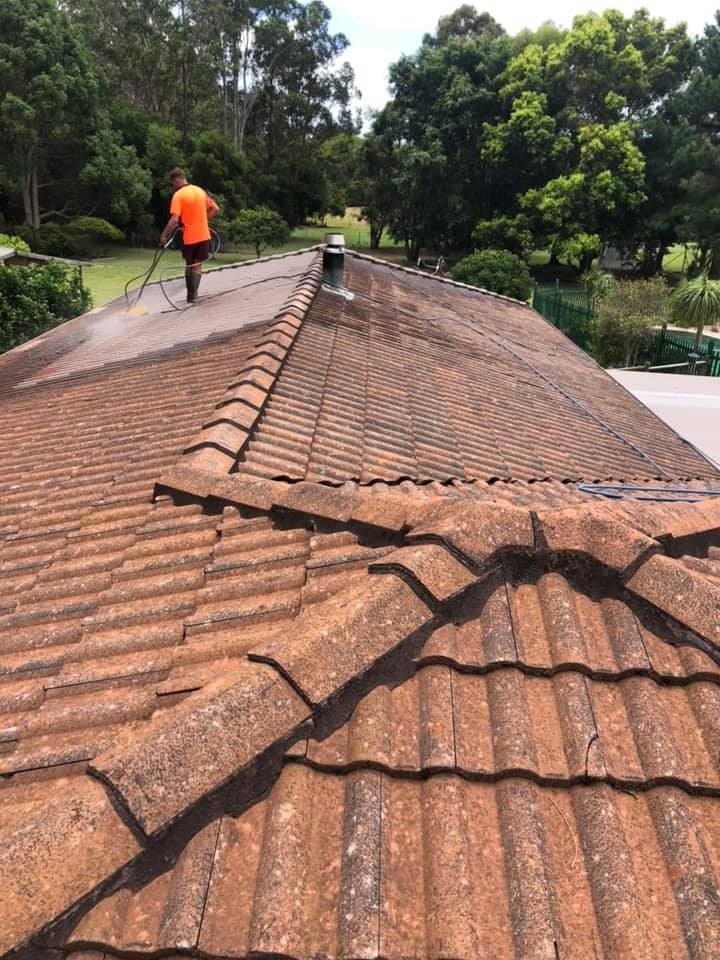 Worker in Orange Shirt Cleaning Roof