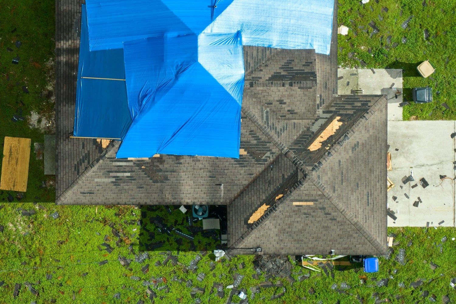 Aerial View of A House with A Blue Tarp Covering Roof Damage — Geoff Hall Roofing in Port Macquarie, NSW