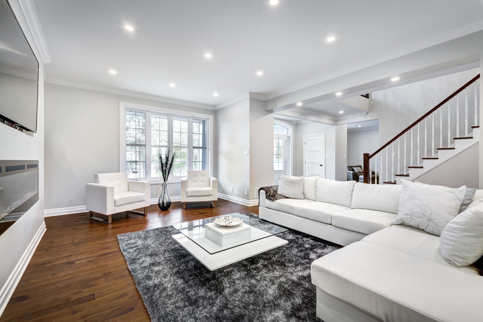 Living room with white sectional sofa, armchairs, and dark wood floors.