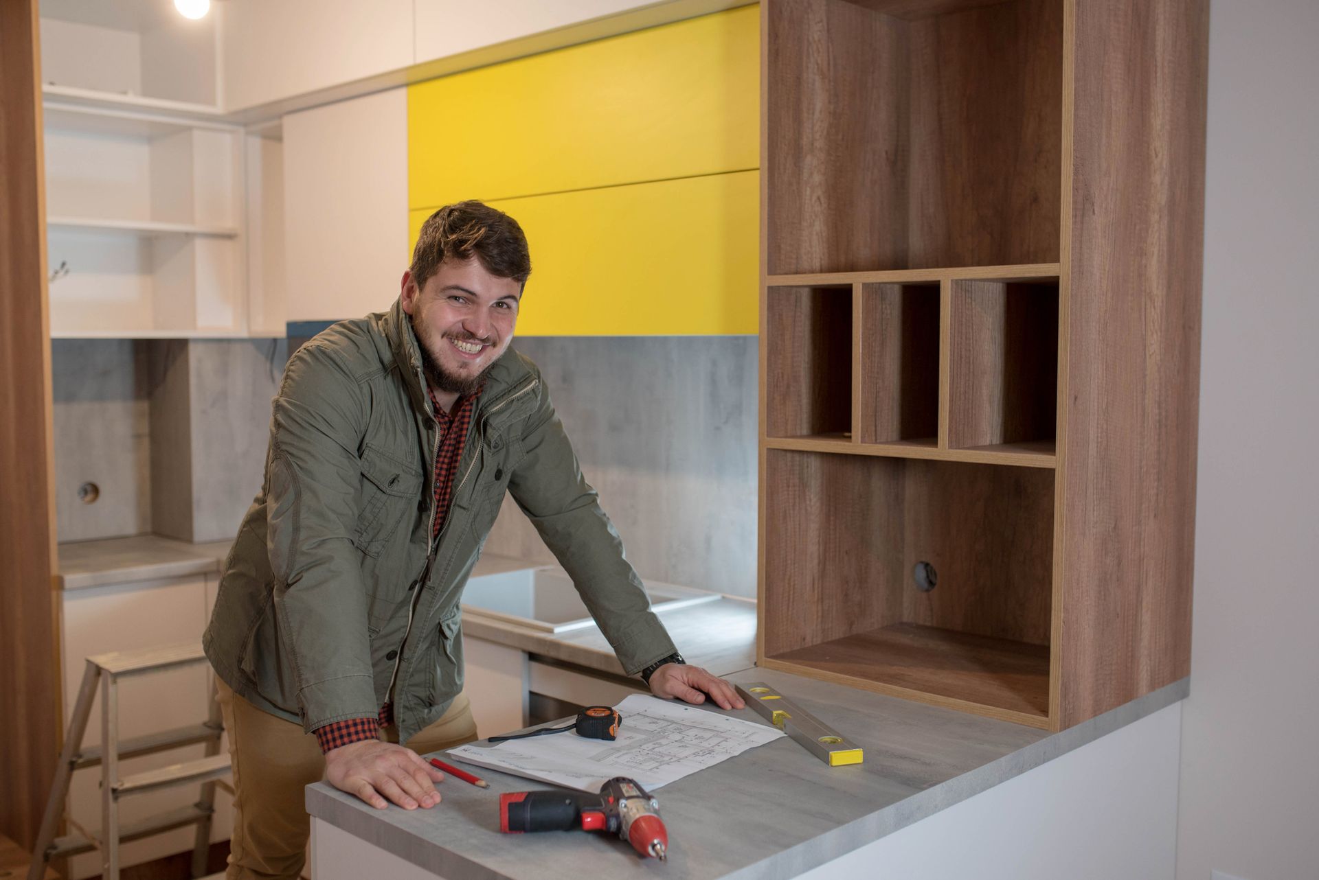 A man stands in a kitchen with tools, indicating a kitchen renovation in progress.