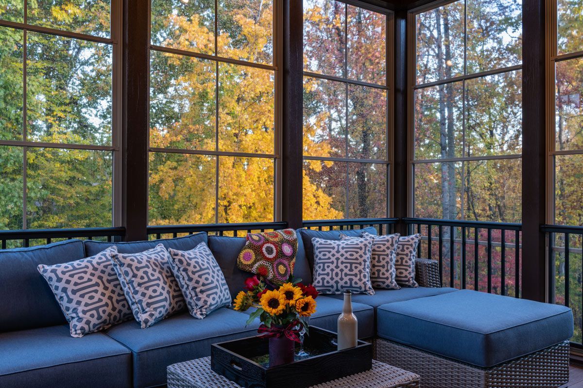 A screened in porch with a couch , table , and ottoman