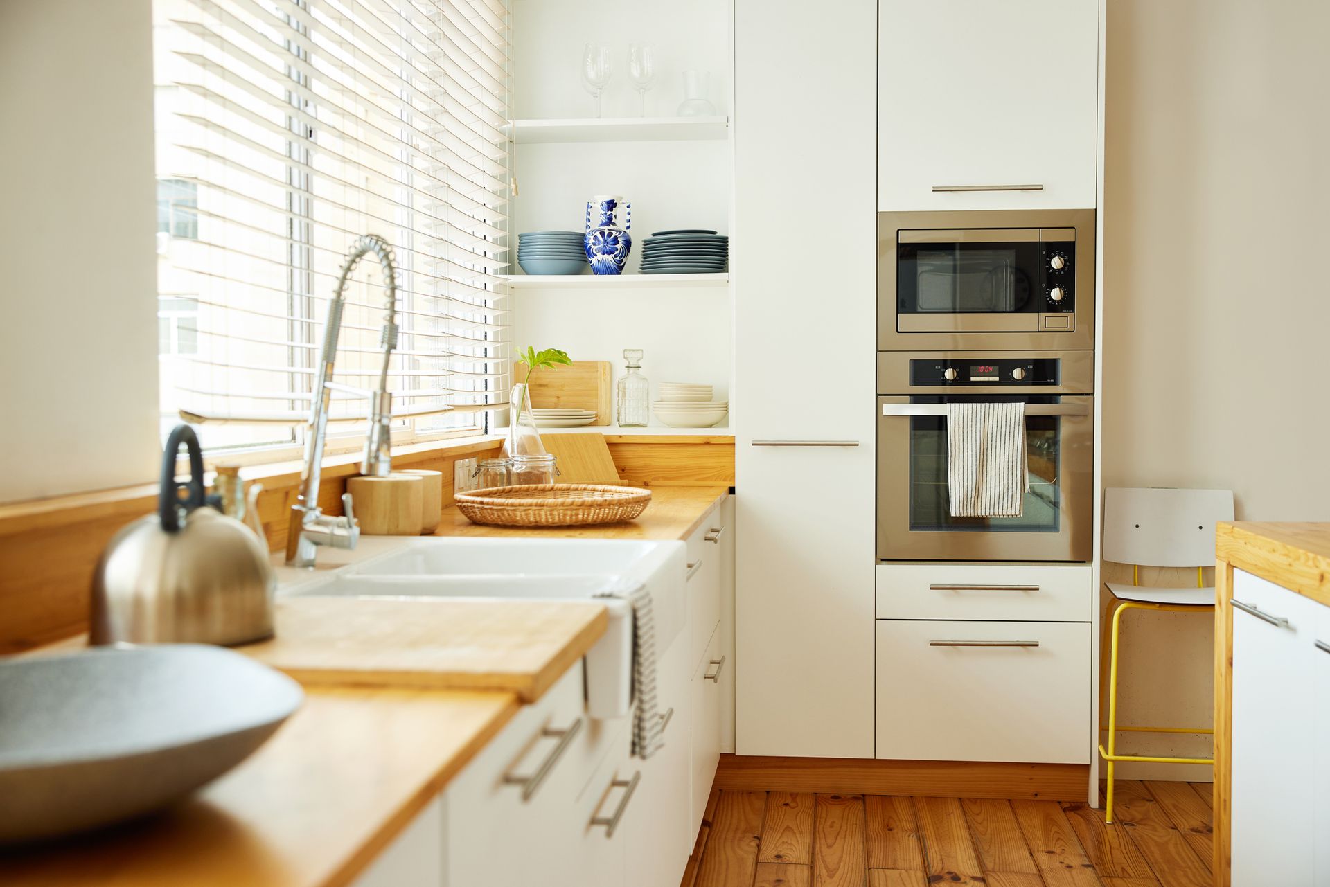 Modern kitchen with wooden countertops, white cabinets, and a stainless steel microwave and oven.