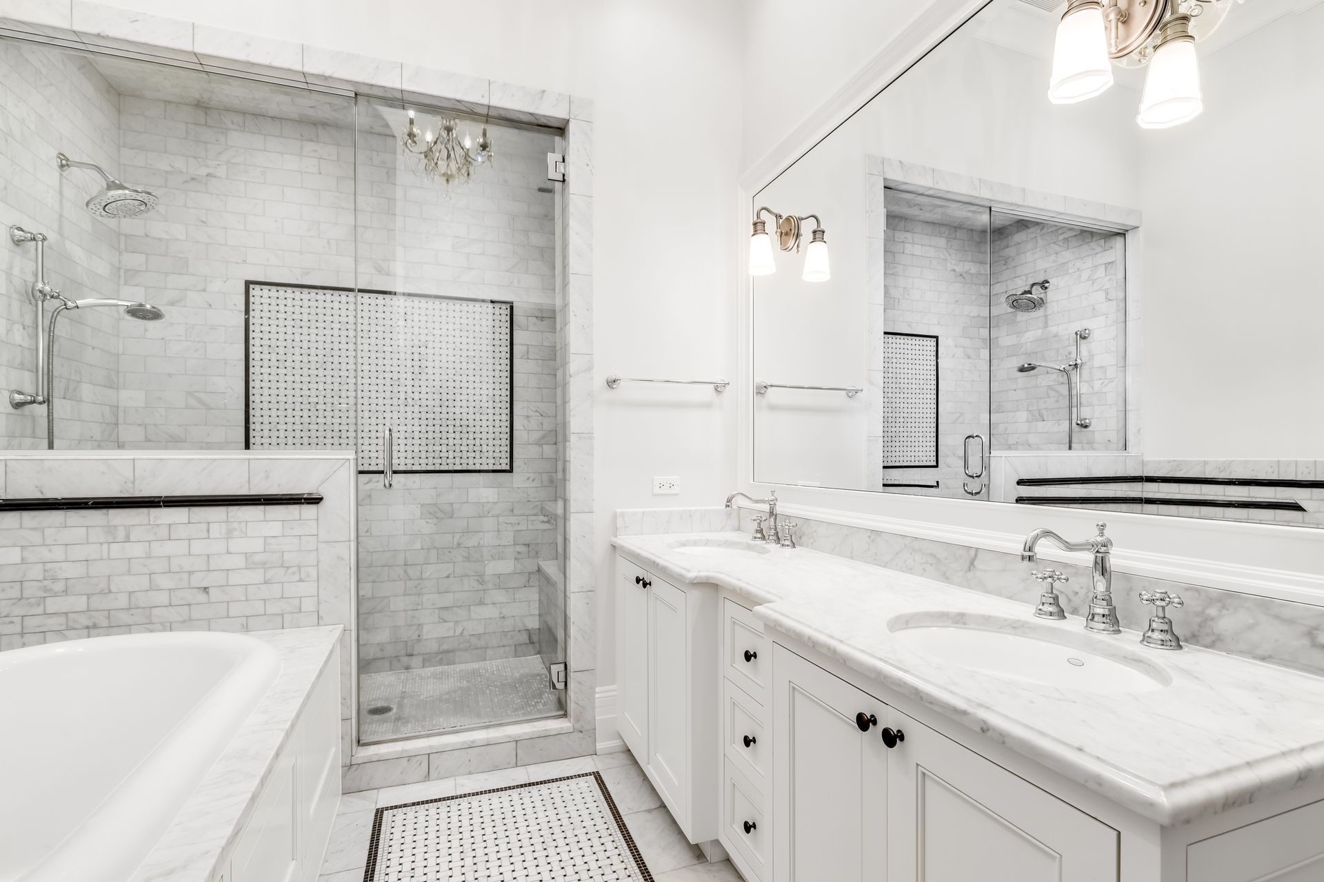 White bathroom with a shower, bathtub, and double sink vanity; marble and tile.