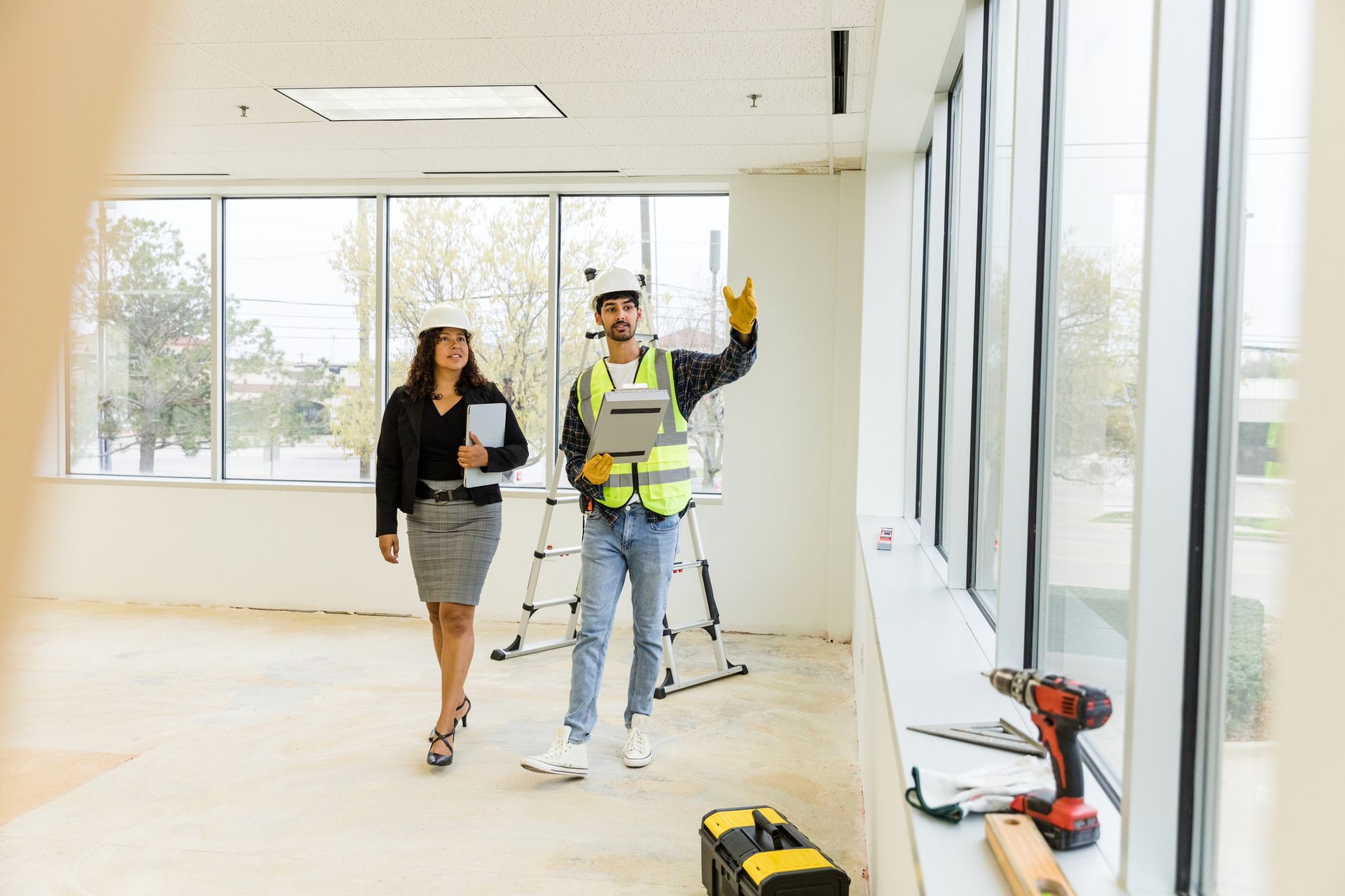 Renovation company contractor and client inspecting office interior with tools on site.