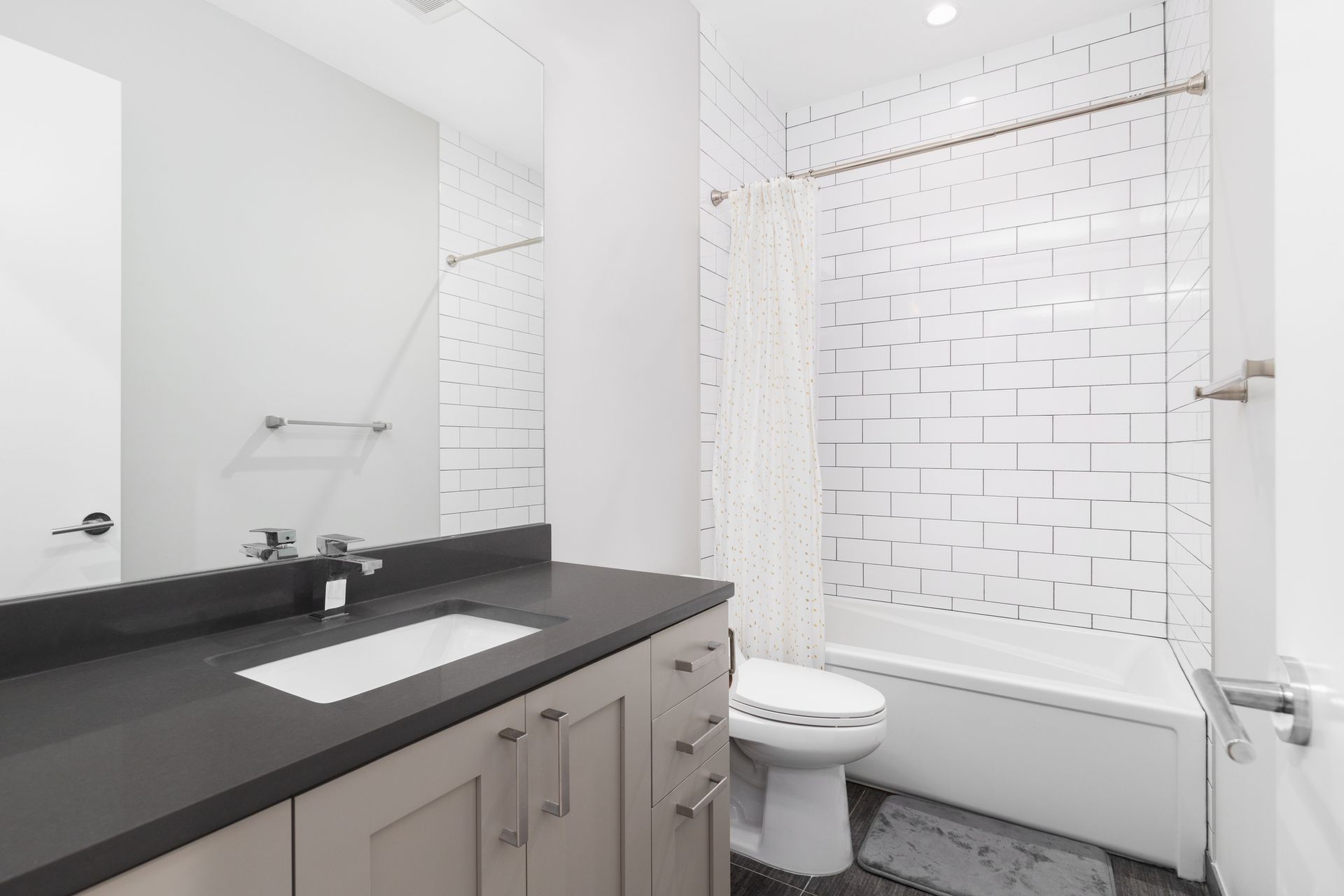 Modern white bathroom with gray countertop and white subway tile shower.