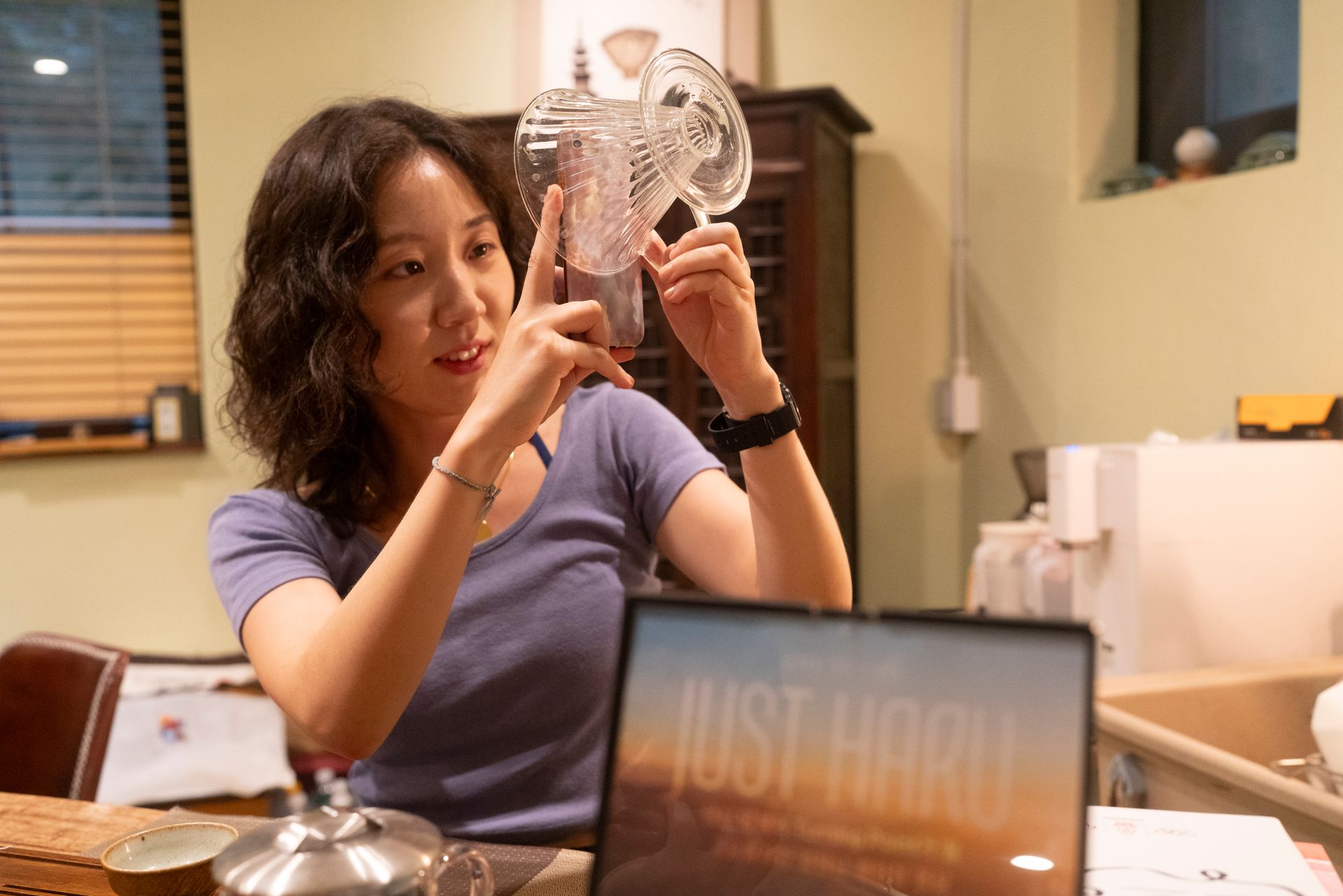 Woman points at a glass object, looking at laptop with 