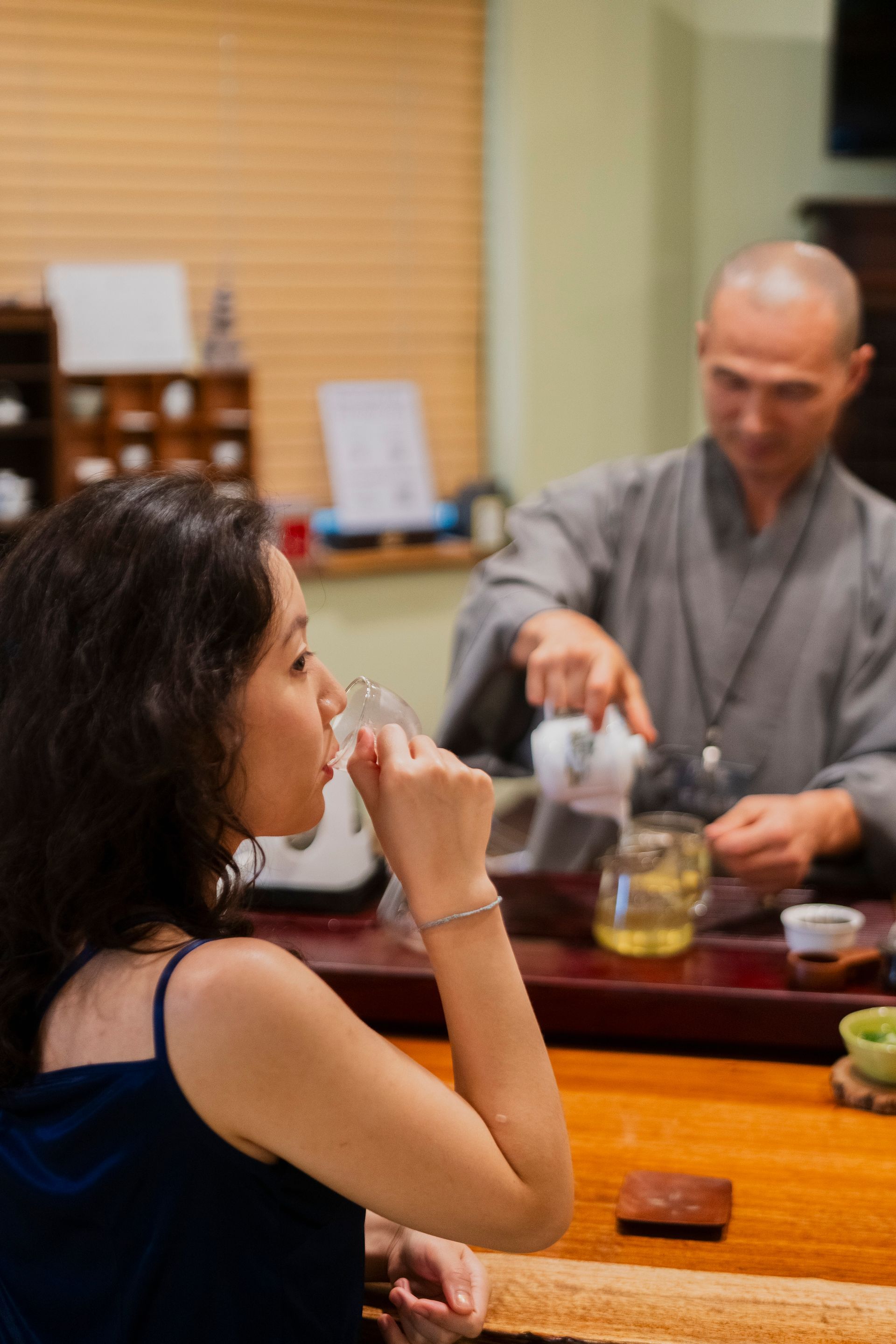 Woman sipping tea as a monk pours tea in a tea ceremony.