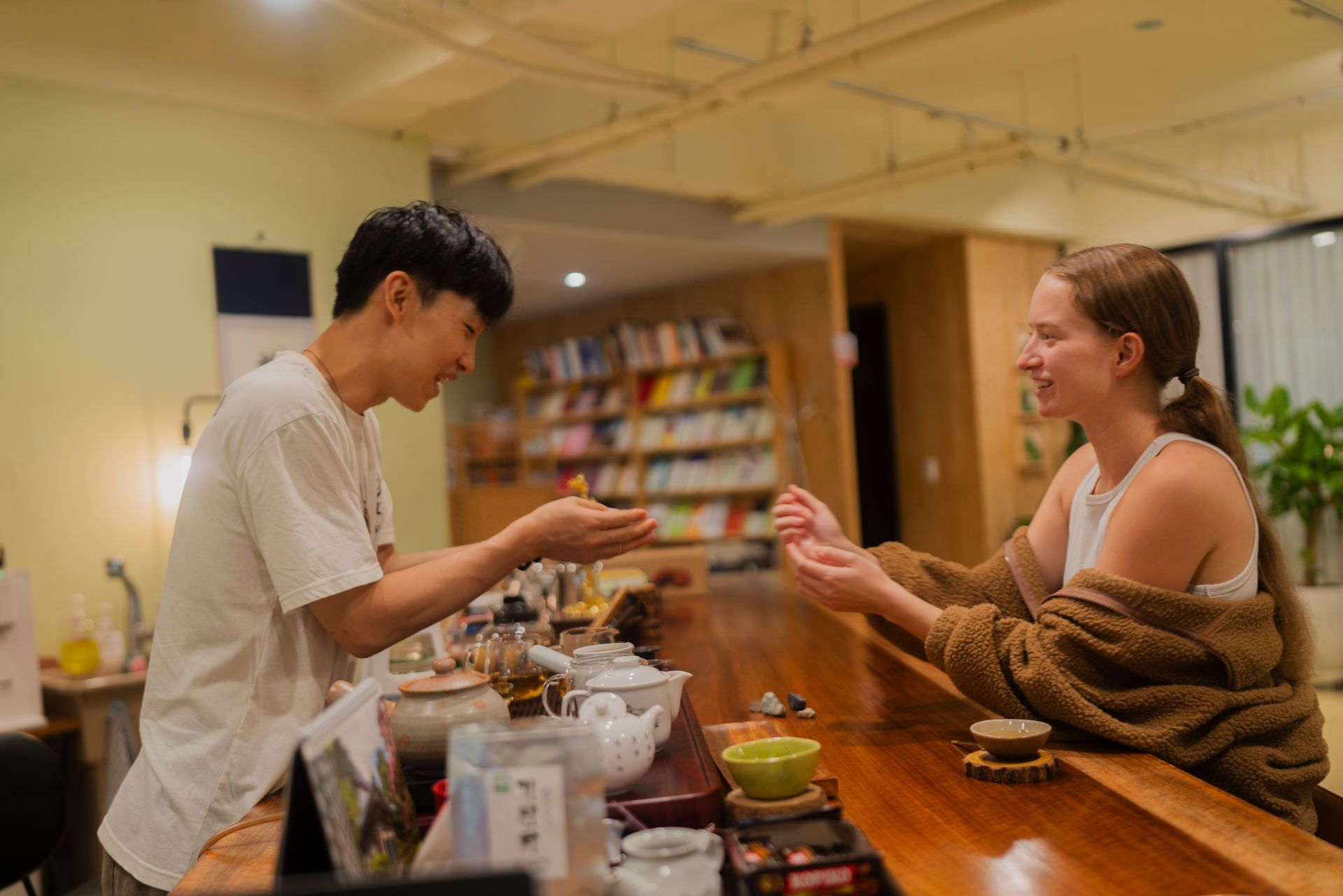 A man serving tea to a woman at a tea bar. They are smiling and interacting.