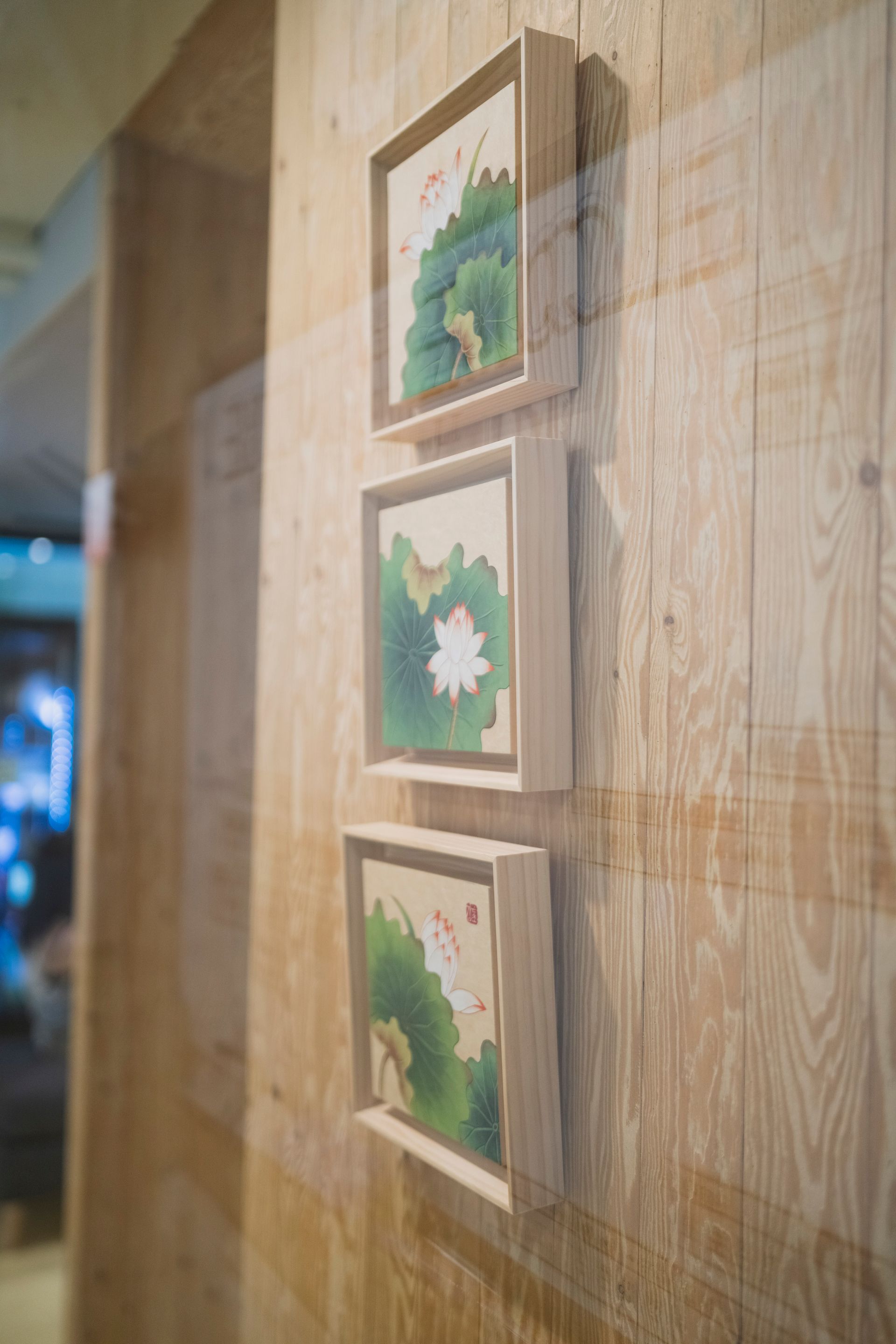 나무 패널로 된 벽에 걸린 연꽃 그림 3개.