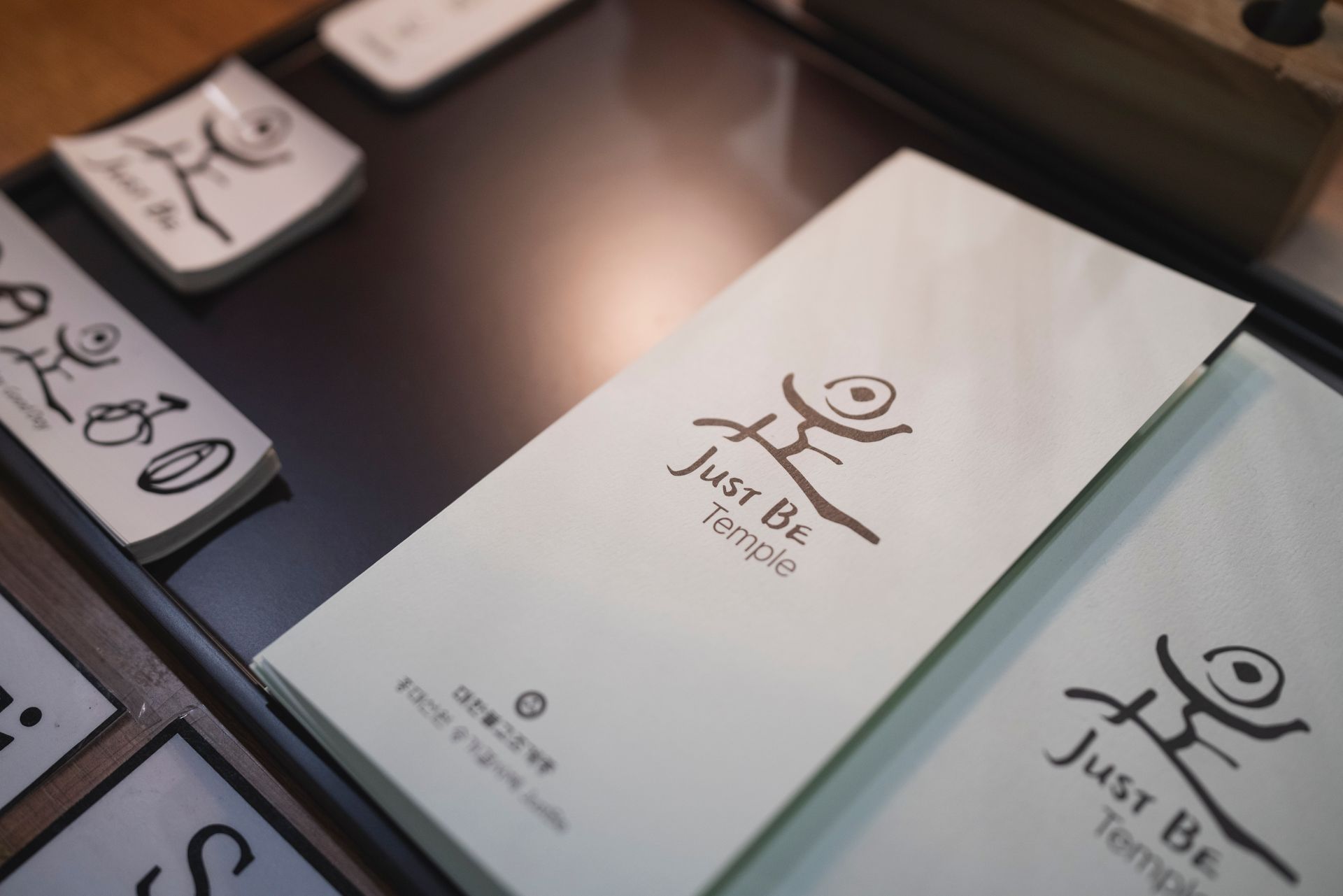 Stack of light green Just Be Temple brochures with brown logo and text.