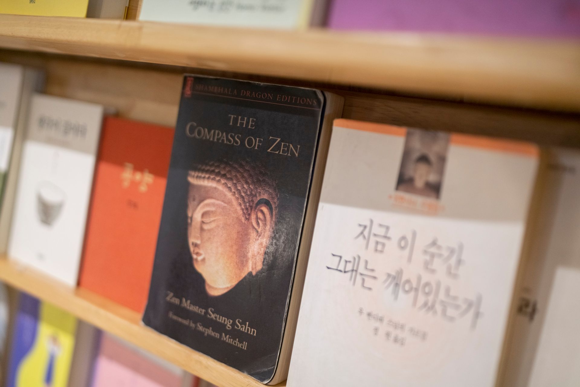 Books on a wooden shelf; one book has a Buddha on the cover, others are in Korean.